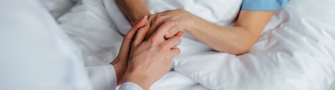 Eine Pflegerin hält die Hand einer Patientin.